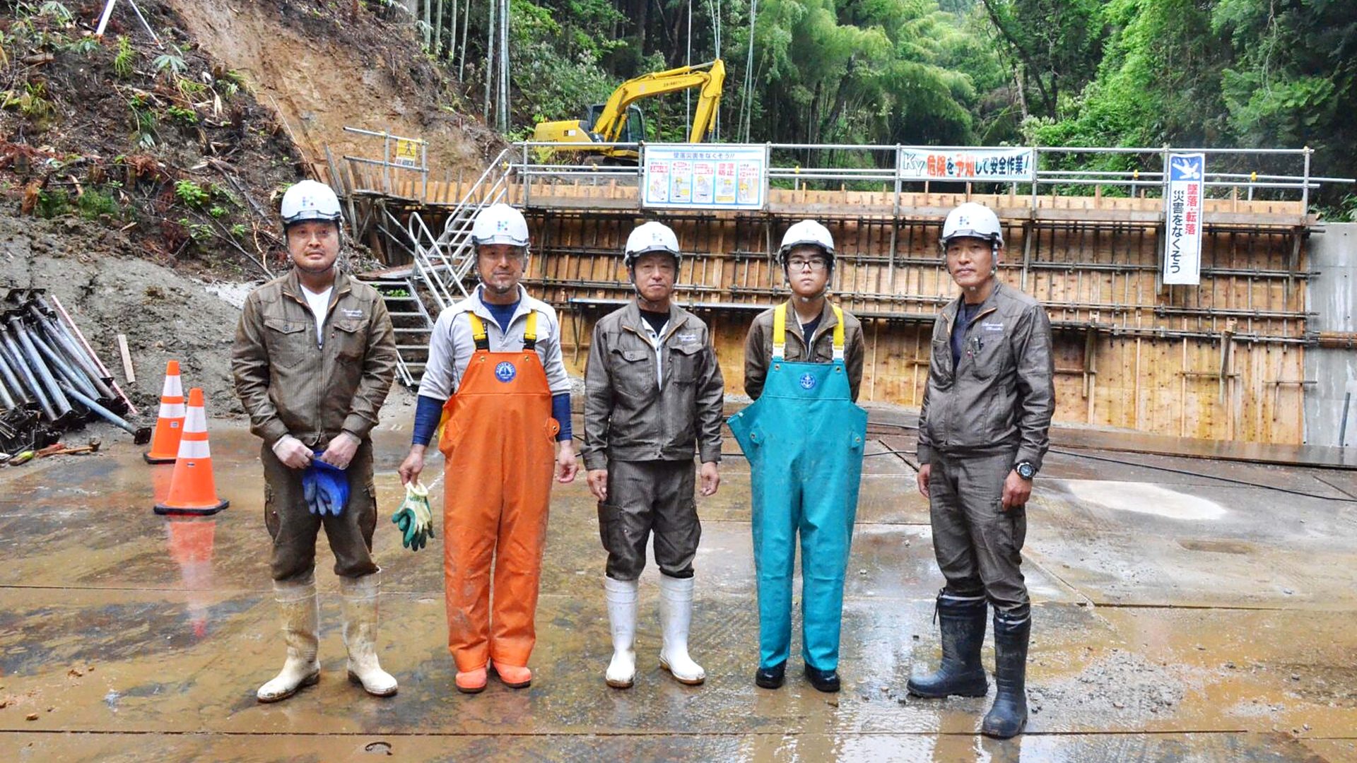 災害復旧工事の現場で並ぶヘルメット姿の社員5人